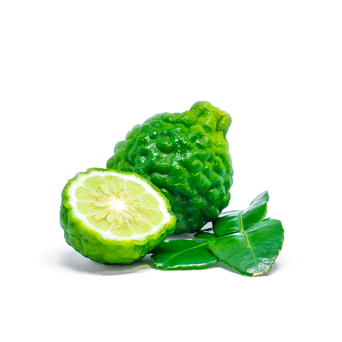 A fresh green bergamot fruit with a bumpy, textured peel, shown whole and sliced in half to reveal its juicy interior, accompanied by glossy bergamot leaves on a white background.